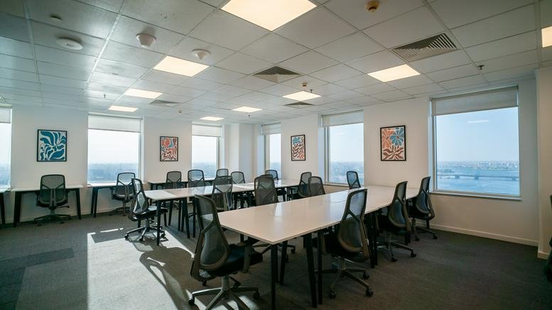 Spacious open-plan workspace with multiple desks and floor-to-ceiling windows.