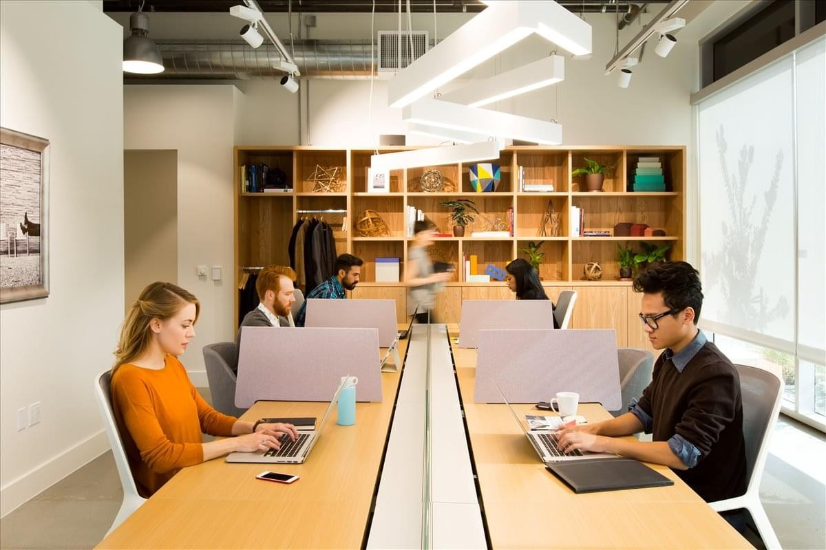 Shared coworking space with warm lighting and wooden workstations at Olin Social District.