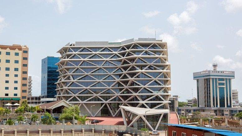 The modern latticed facade of One Airport Square under a bright blue sky.