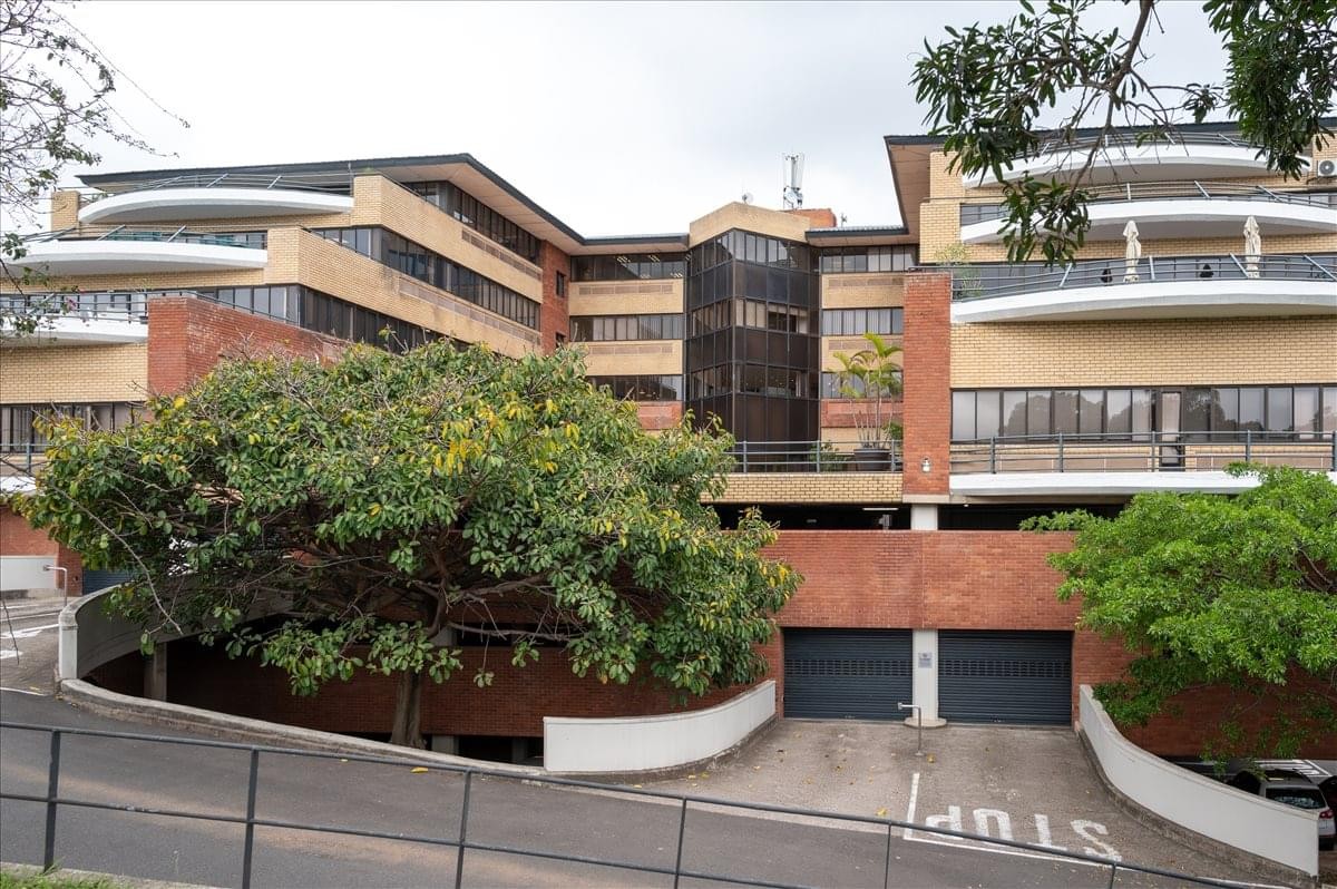 Exterior view of the multi-story Pharos House building with brick accents and greenery.