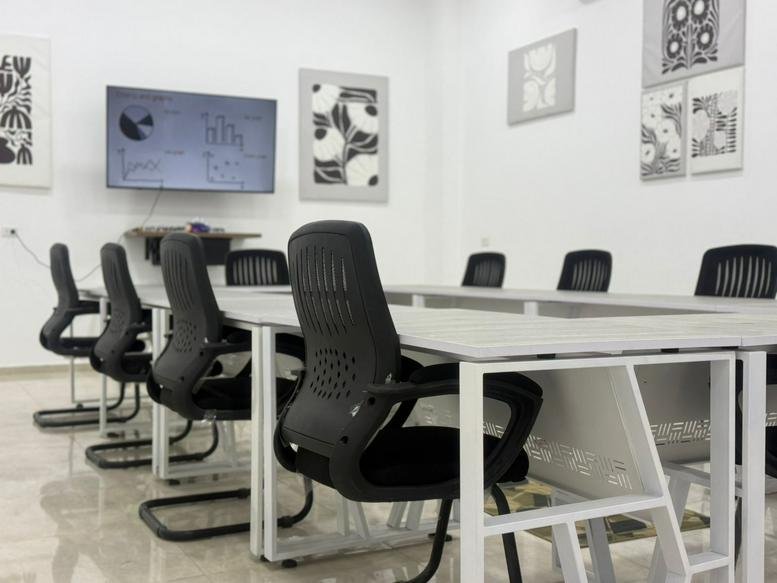 Spacious professional meeting room at Qroo Workspace, Hijaz Road, Hurghada, Egypt with modern black mesh chairs.