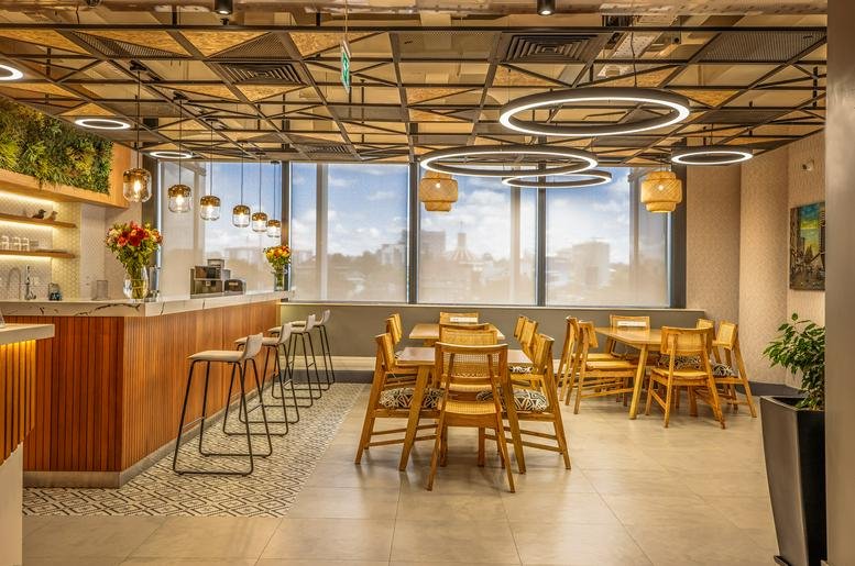 Spacious communal dining area with modern wooden tables and distinctive circular light fixtures.