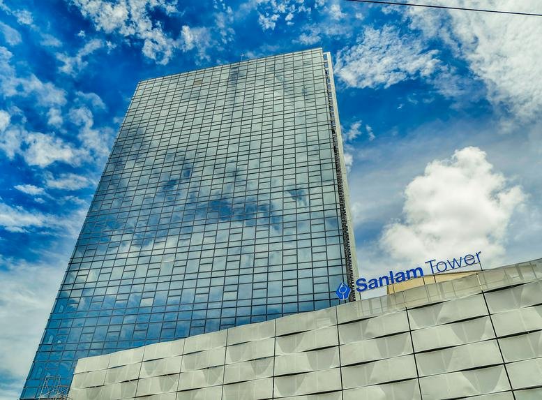 Low-angle exterior view of the glass-facade Sanlam Tower against a blue sky.
