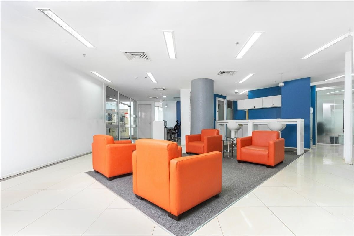 Communal breakout lounge featuring vibrant orange armchairs and a blue accent wall.