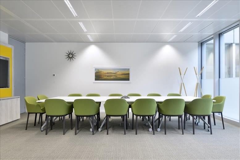 Large meeting room with a long table and green chairs under spotlights.