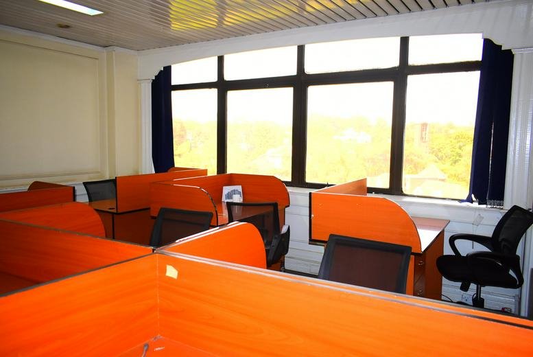 Large open-plan coworking area with orange-partitioned desks by a large window.
