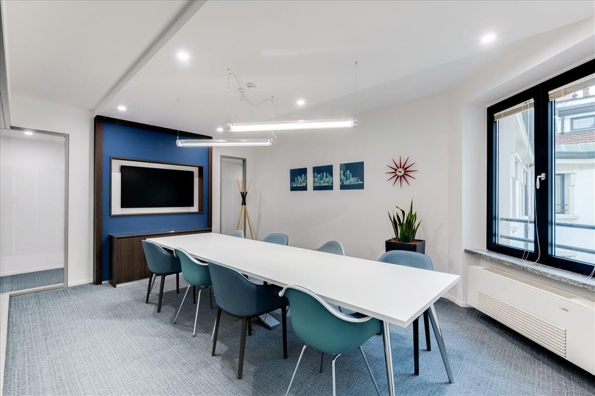 Meeting room at 4th Floor, Vision Plaza with a long white table, teal chairs, and a blue accent wall.