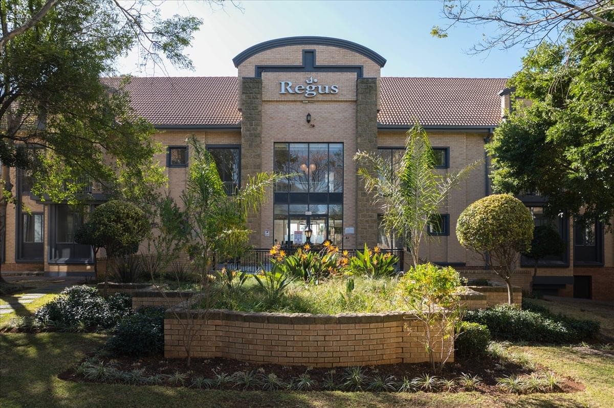 Exterior view of the manicured gardens and tan facade of Wedgefield Office Park.