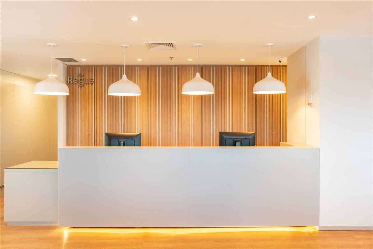 Modern reception desk with wooden wall panelling and warm pendant lighting.