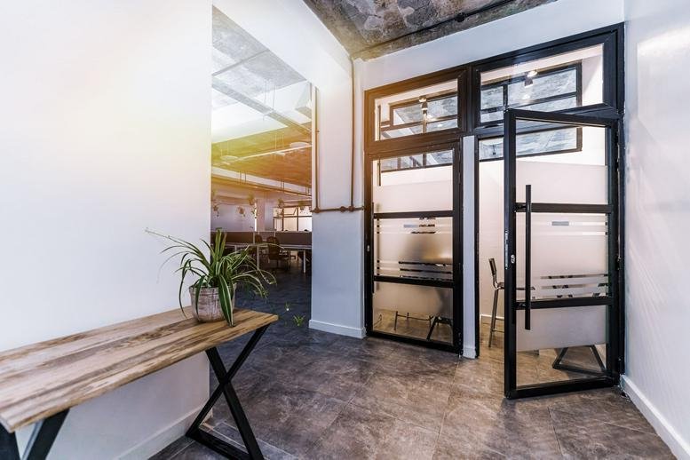 Entrance area of the Delta Corner Annex with a wooden console table, potted plant, and glass doors.