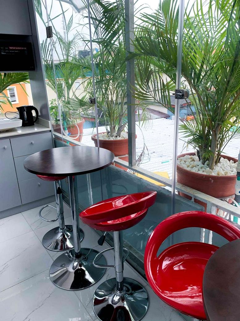 Communal break area at 2nd Floor, Wing 5, 4C Idowu Martins Street with red bar stools and potted palm trees.