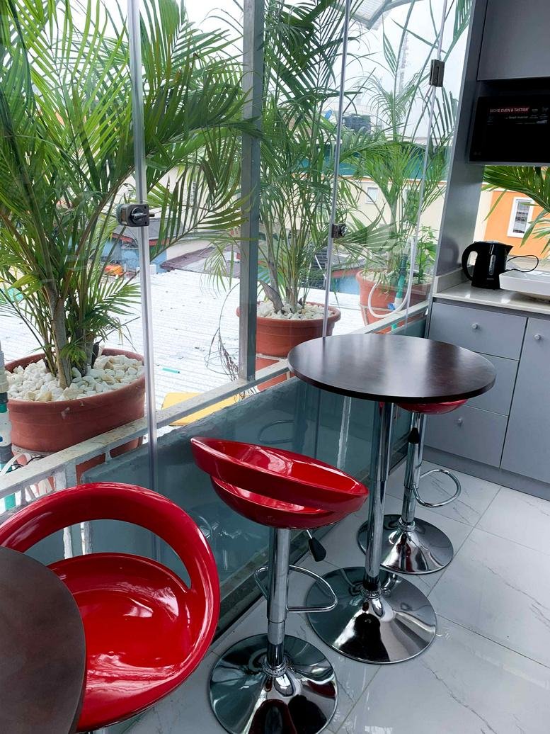 Bright breakout space at 2nd Floor, Wing 5, 4C Idowu Martins Street featuring tall red chairs and greenery.
